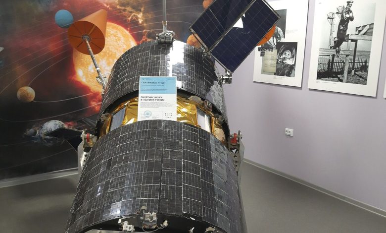 A communications satellite orbiting Earth with solar panels extended above the planet's curved horizon.